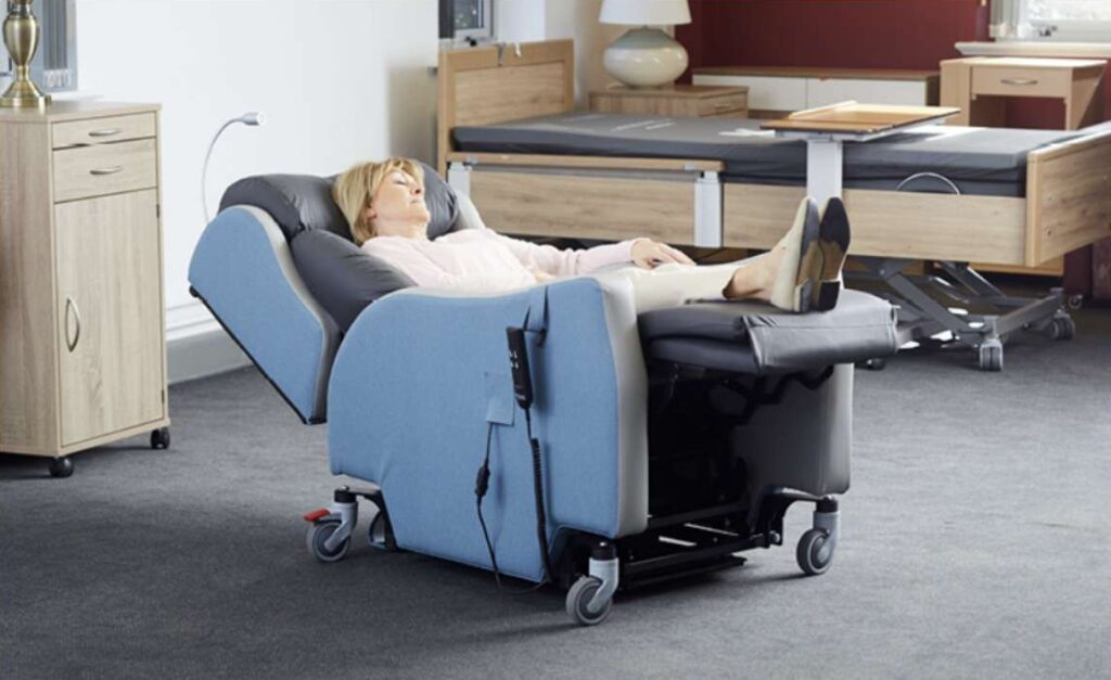 Lifestyle shot of the ProSpec hospital riser recliner chair with an elderly woman in a fully reclined position. The picture is indoors, and the room is carpeted.