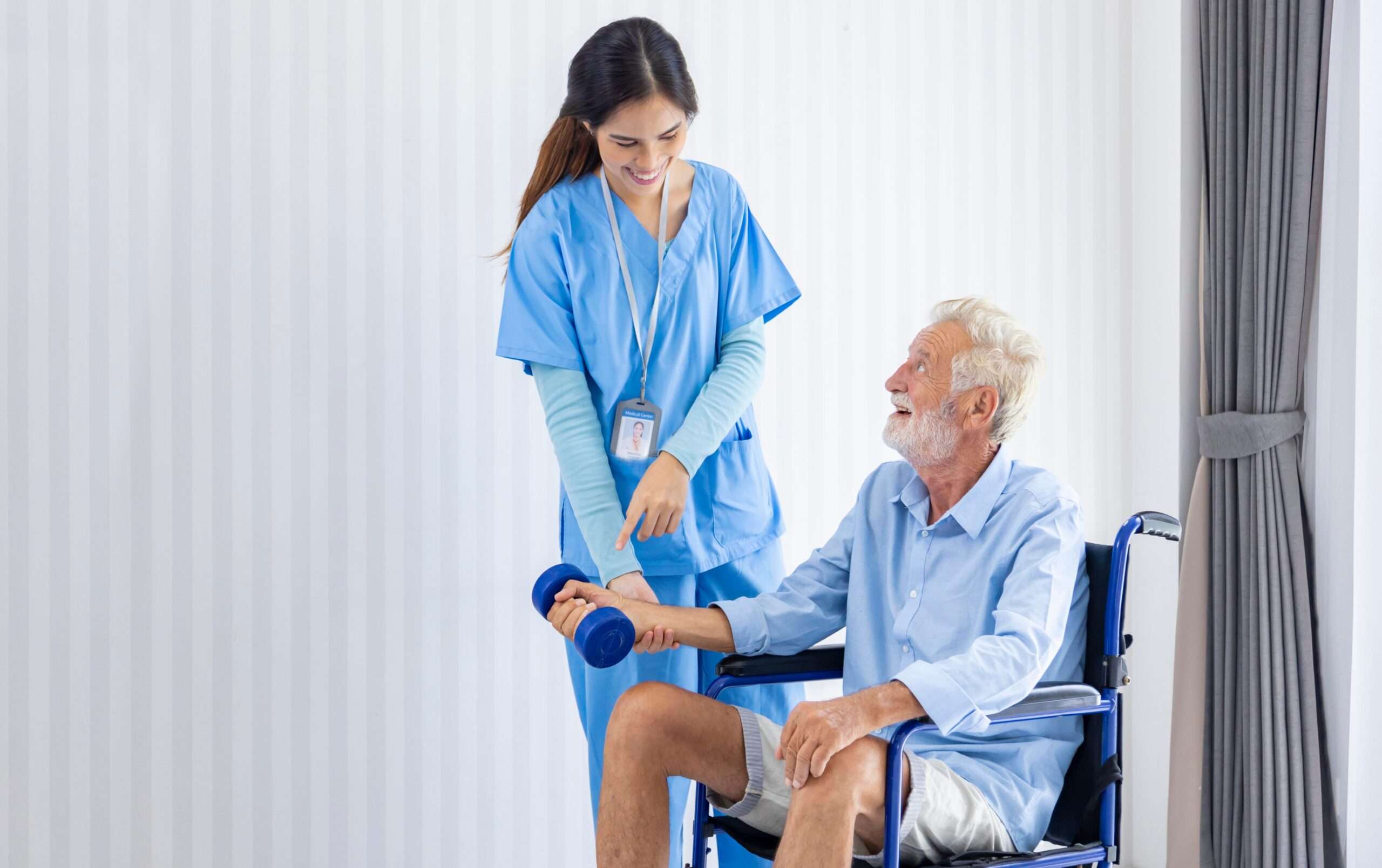 Hospice nurse is helping Caucasian man in wheelchair to exercising muscle strength at pension retirement center for home care rehabilitation and post treatment recovery process